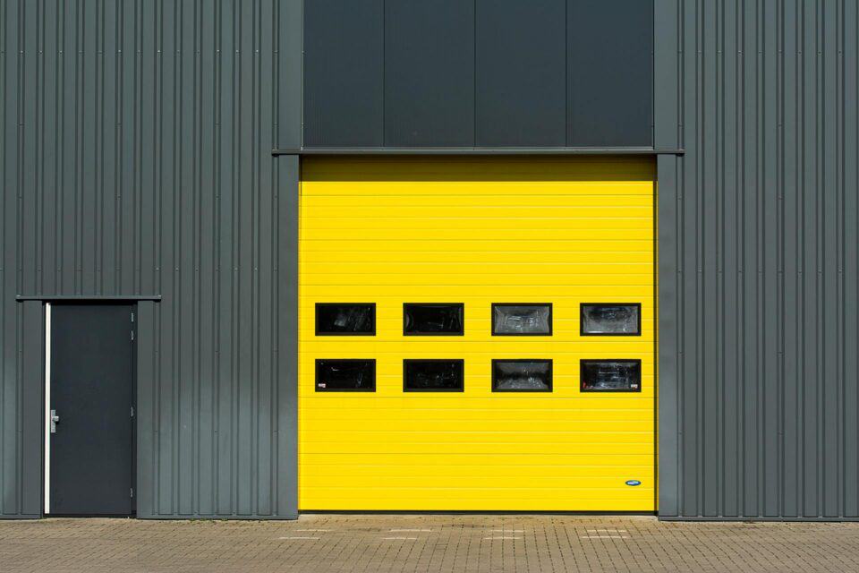 bright yellow metal door against dark gray and black commercial building