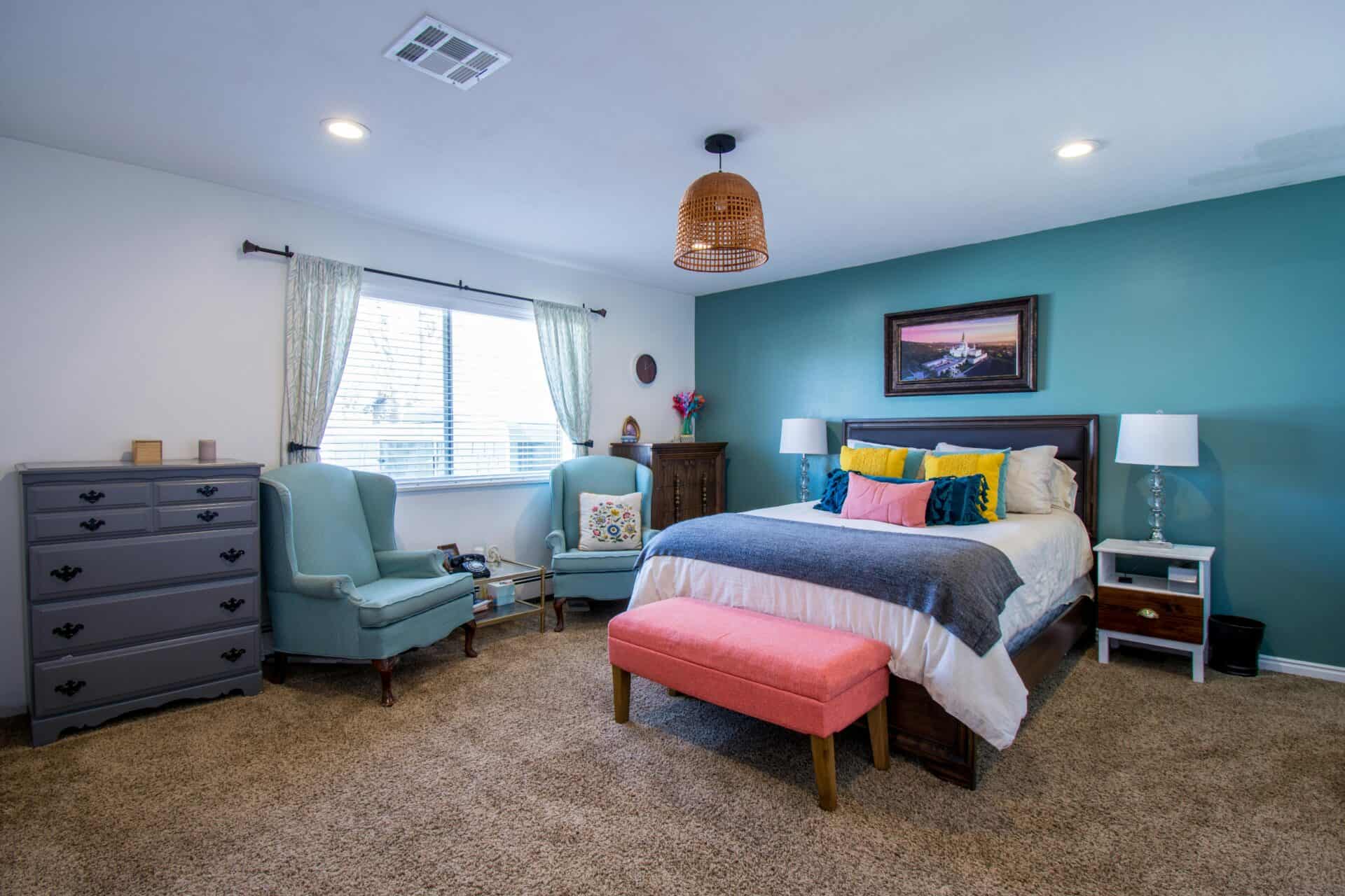 A bright, colorful bedroom with a teal blue painted accent wall.
