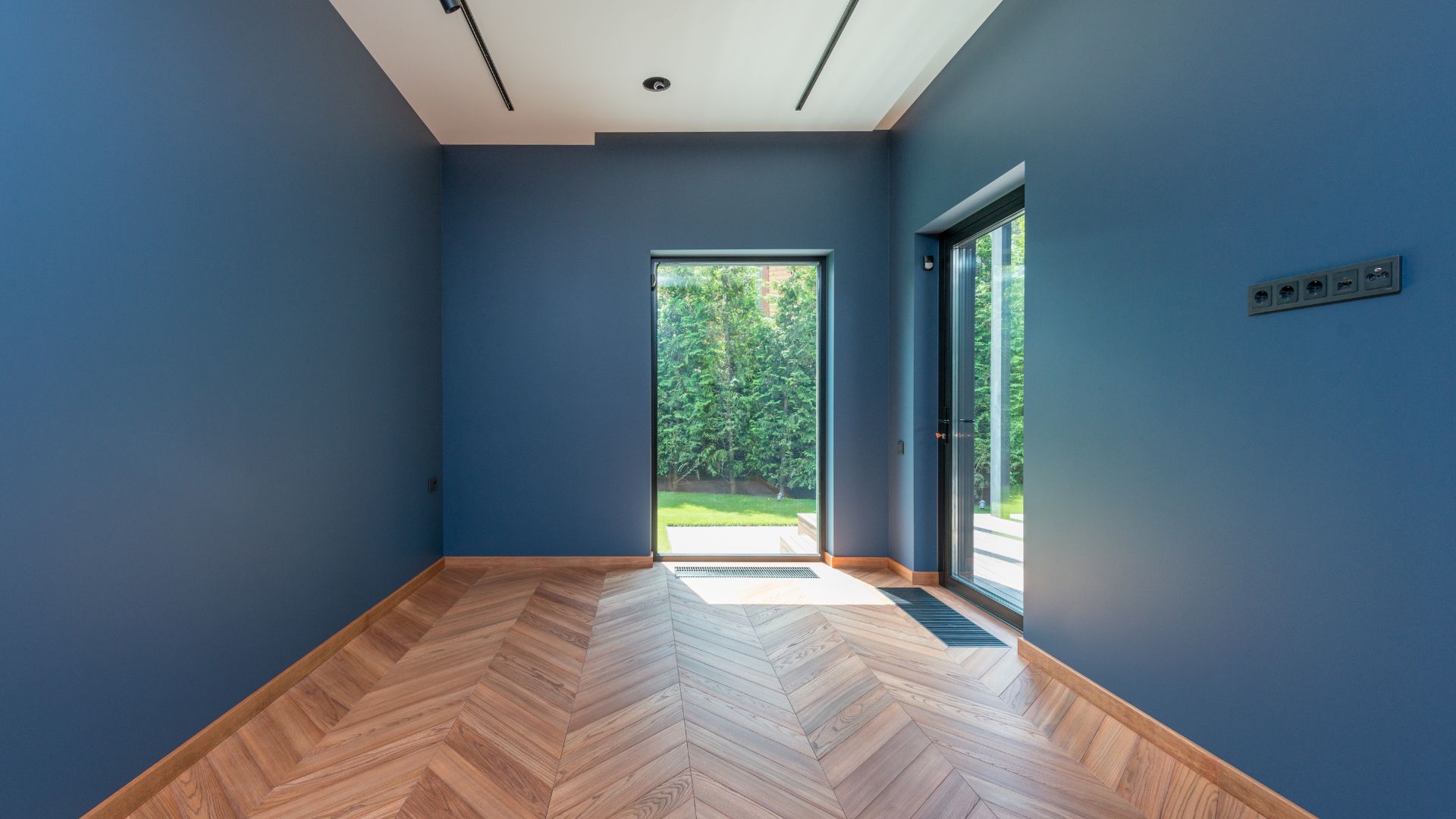 An empty room with blue walls, white ceiling, and a hardwood floor.