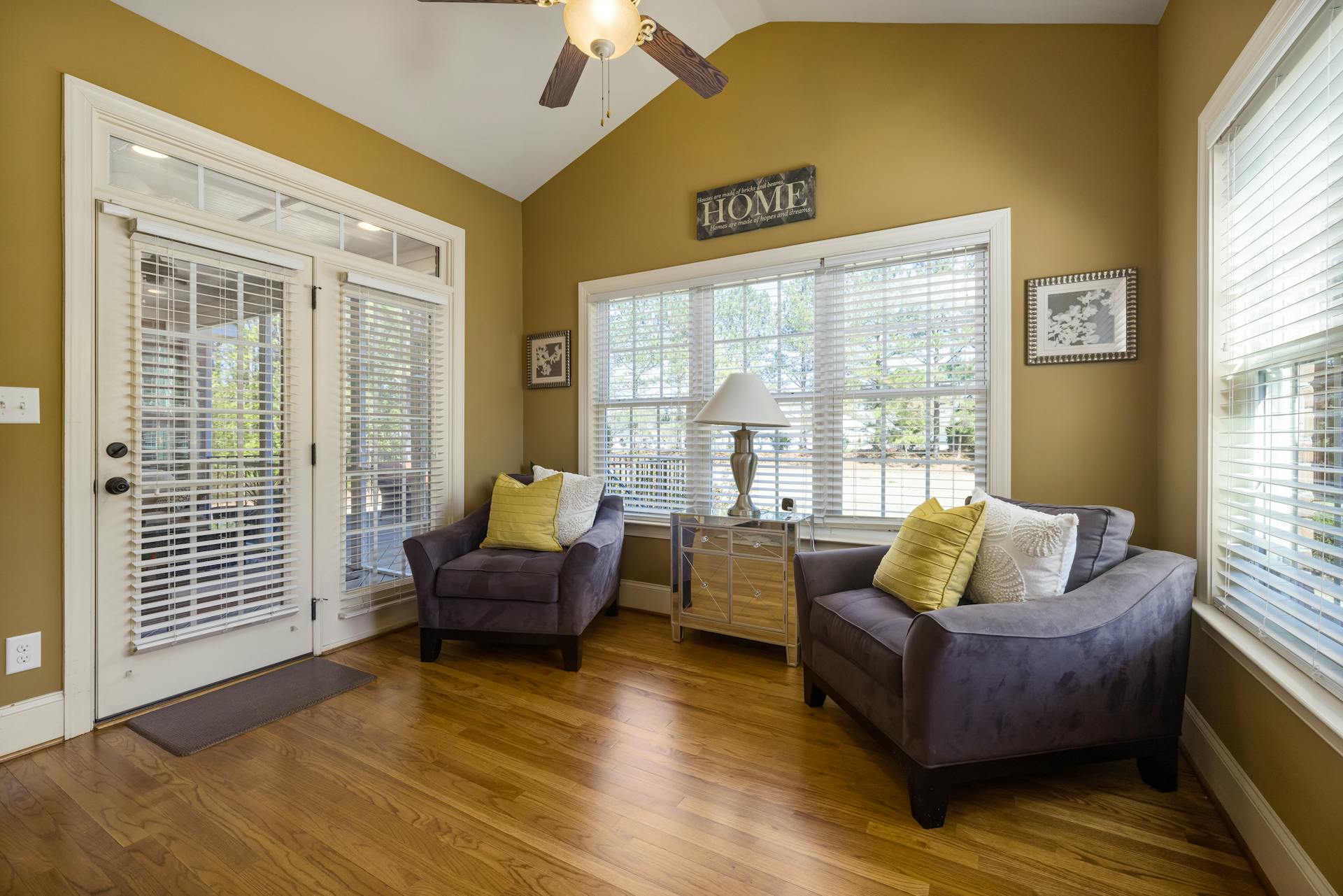 A furnished room with mustard yellow painted walls, white ceiling and trim, and a sign on wall that reads Home.