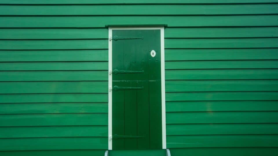 A dark green door against a vibrant green exterior wall.