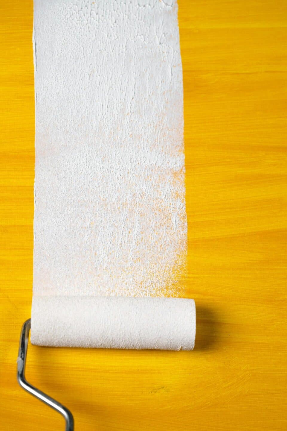 paint roller painting white over yellow color